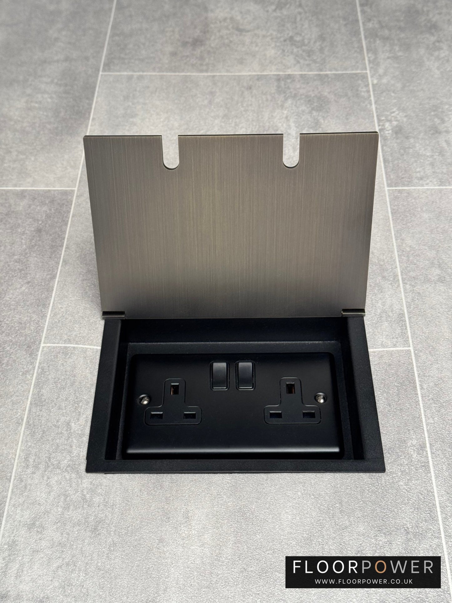 Antique brass recessed floor socket with a double 13amp switched plug socket, in a tiled floor.