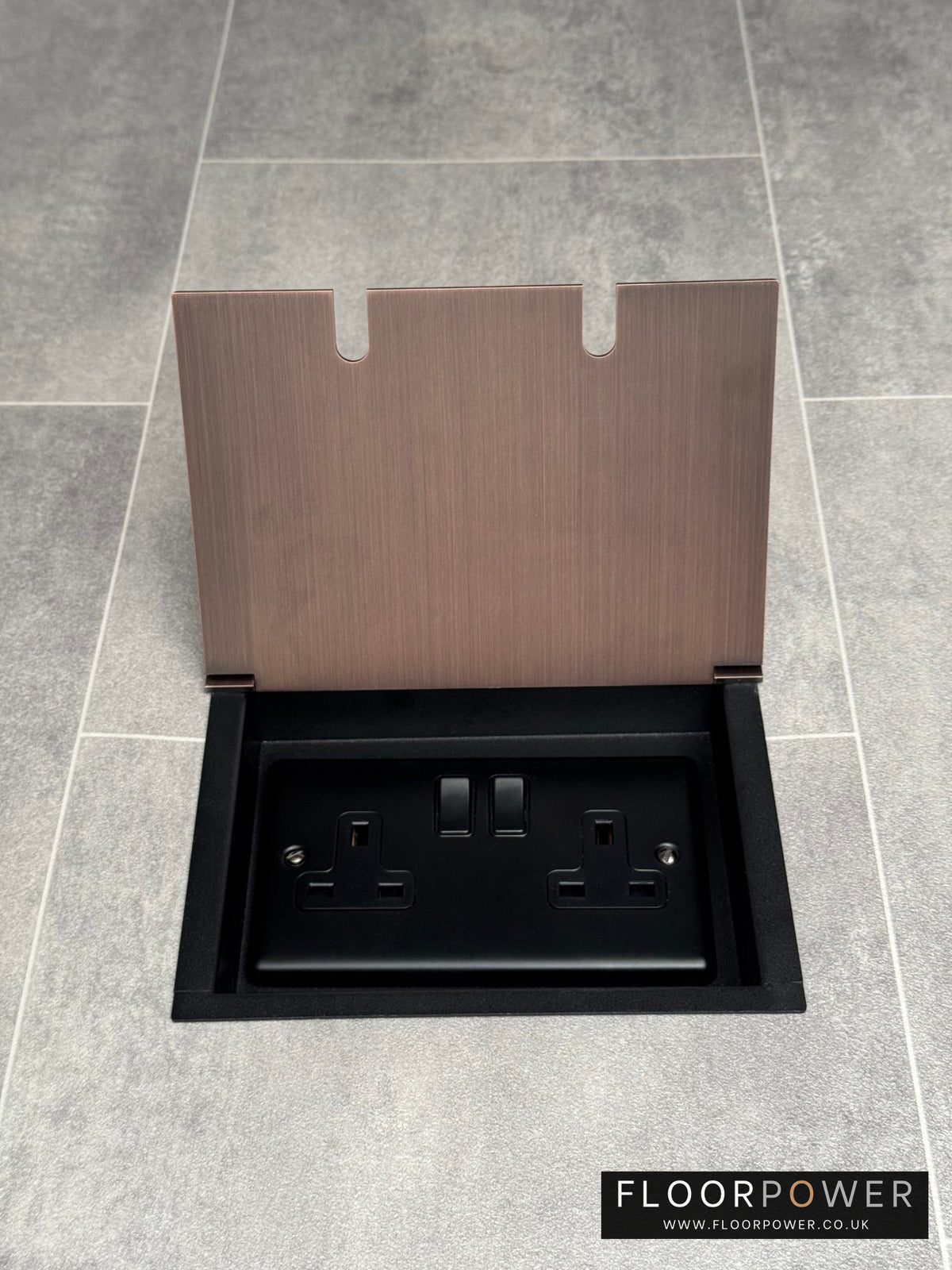A double 13 Amp switched plug socket in an antique copper recessed floor socket.