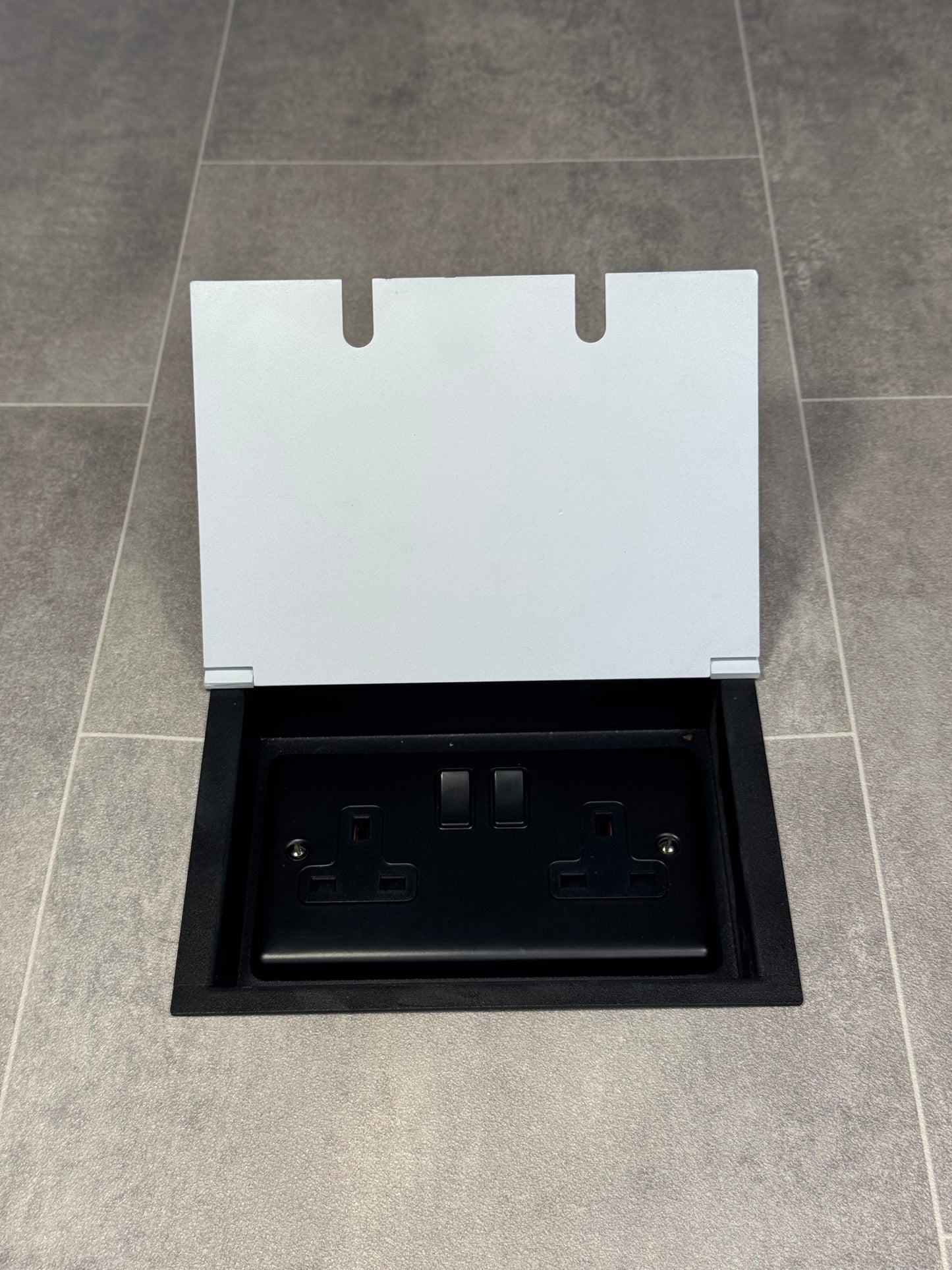 A white double recessed floor socket with a 13 amp switched plug socket installed in a floor.