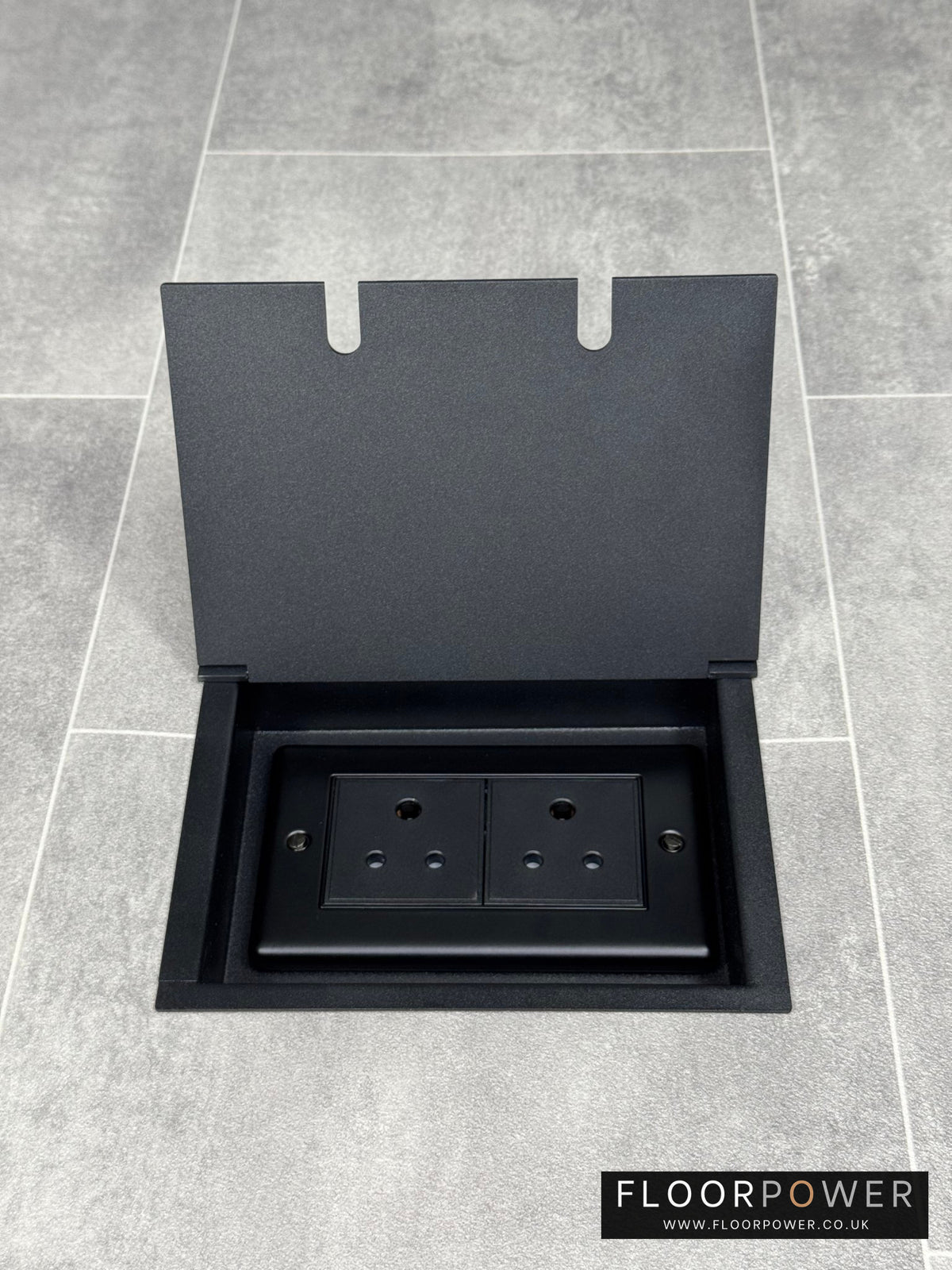 Double 5 amp recessed floor socket for lighting with matt black lid set into the floor.