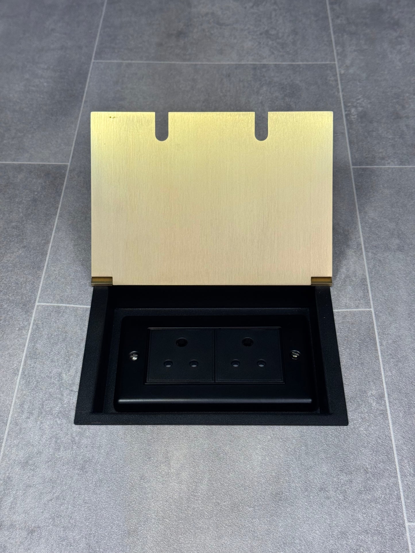 Double 5 amp recessed floor socket for lighting with satin brass lid set into the floor.