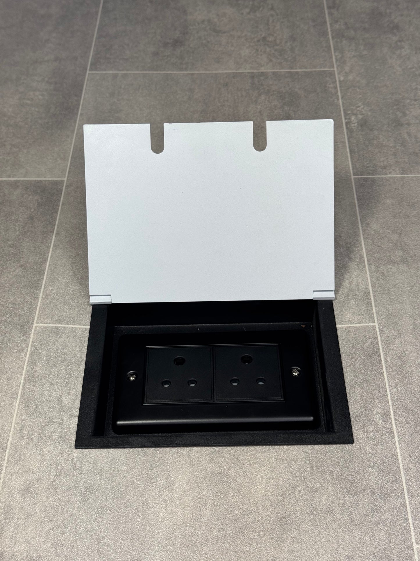 Double 5 amp recessed floor socket for lighting with white lid set into the floor.
