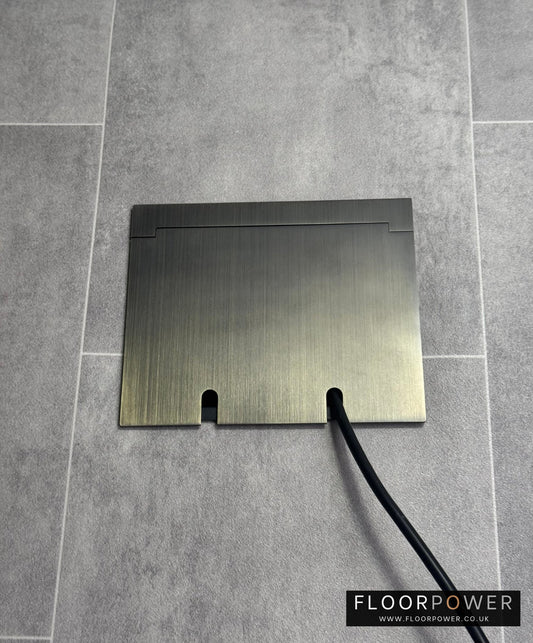 Double Antique Brass Recessed Floor Socket With Lid Closed Flat Showing Just Cable Coming Out If The Socket - Front On View.