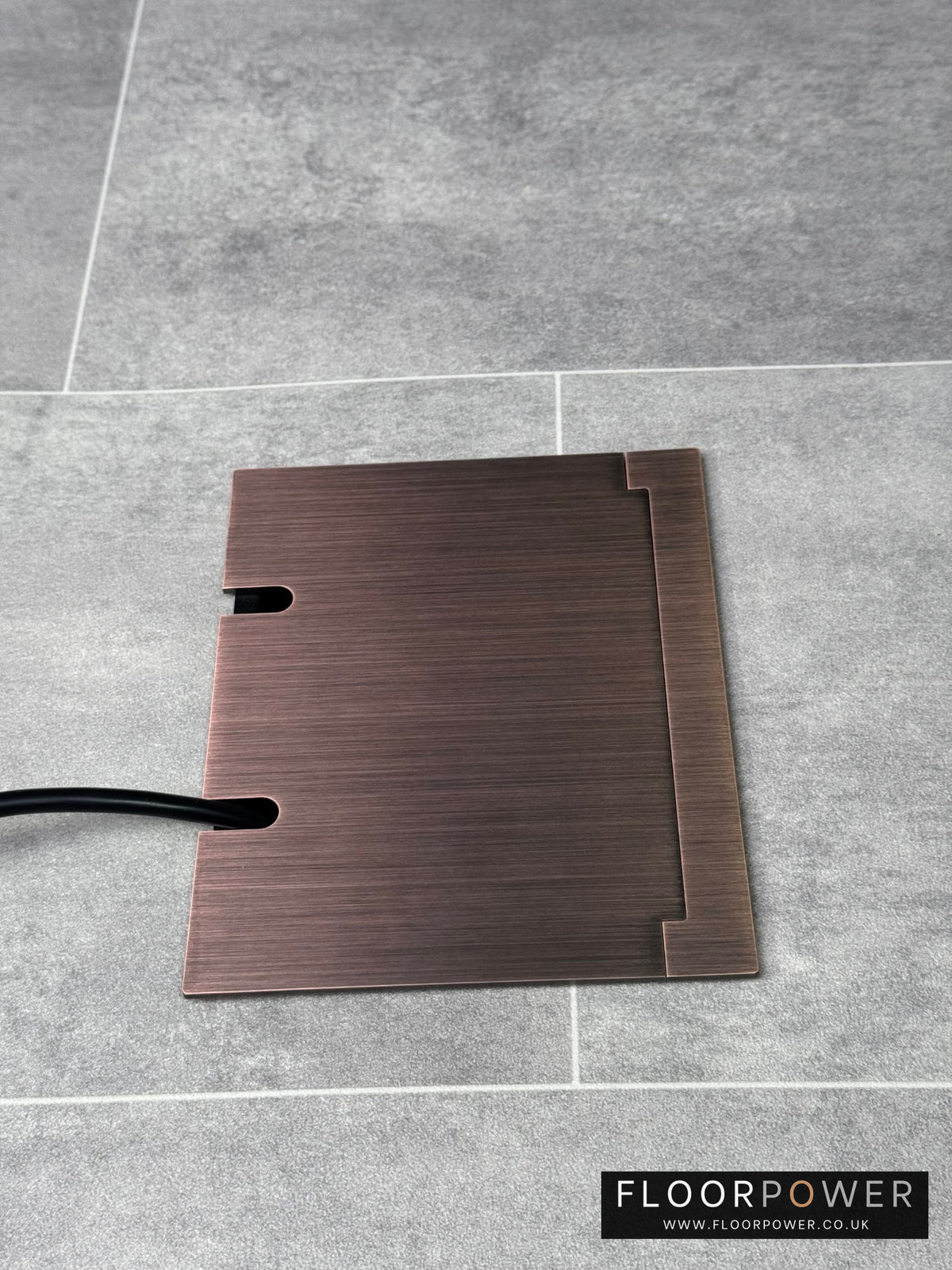 Double Antique Copper Recessed Floor Socket With Lid Closed Flat Showing Just Cable Coming Out If The Socket - Side On View.