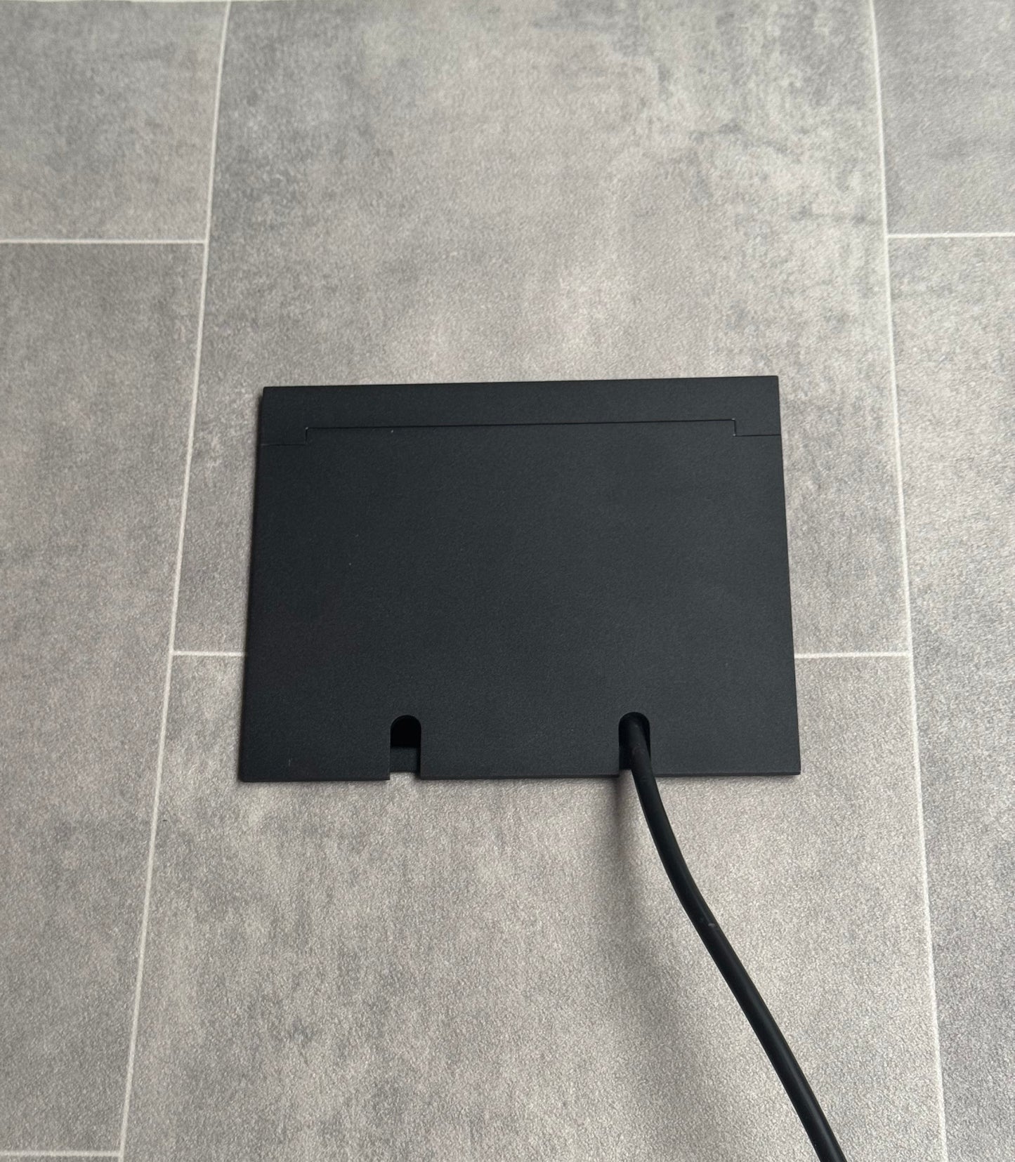 Double Matt Black Recessed Floor Socket With Lid Closed Flat Showing Just Cable Coming Out If The Socket - Front On View