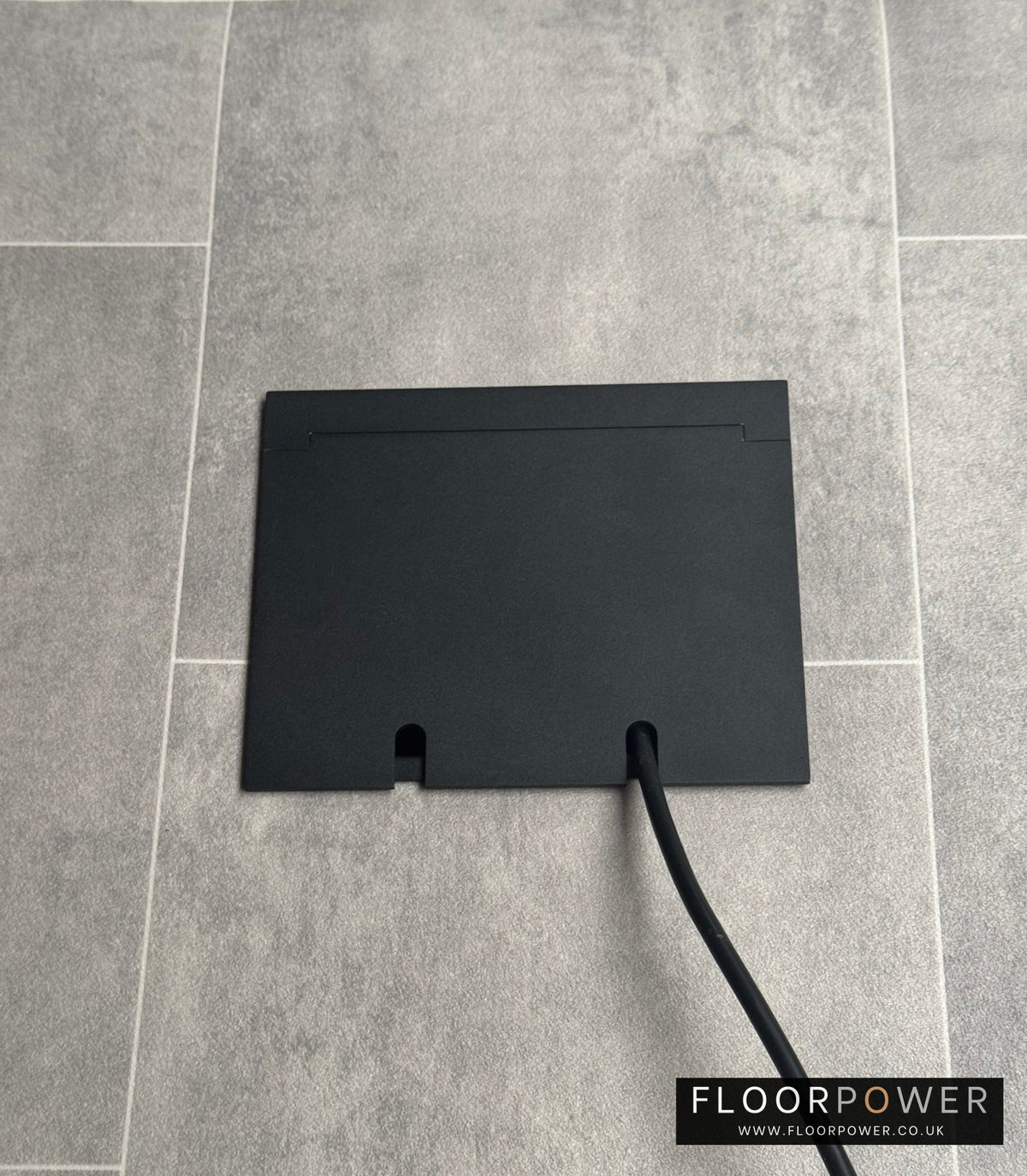Double Matt Black Recessed Floor Socket With Lid Closed Flat Showing Just Cable Coming Out If The Socket - Front On View