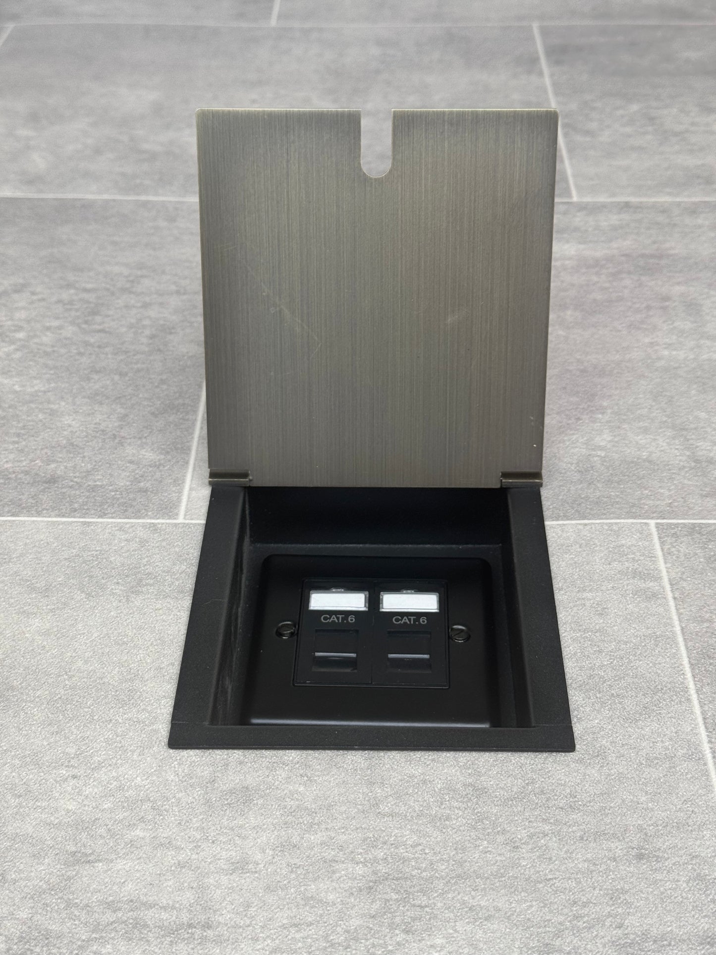A recessed floor socket with an antique brass cover, two RJ45 sockets, designed for network cable management.