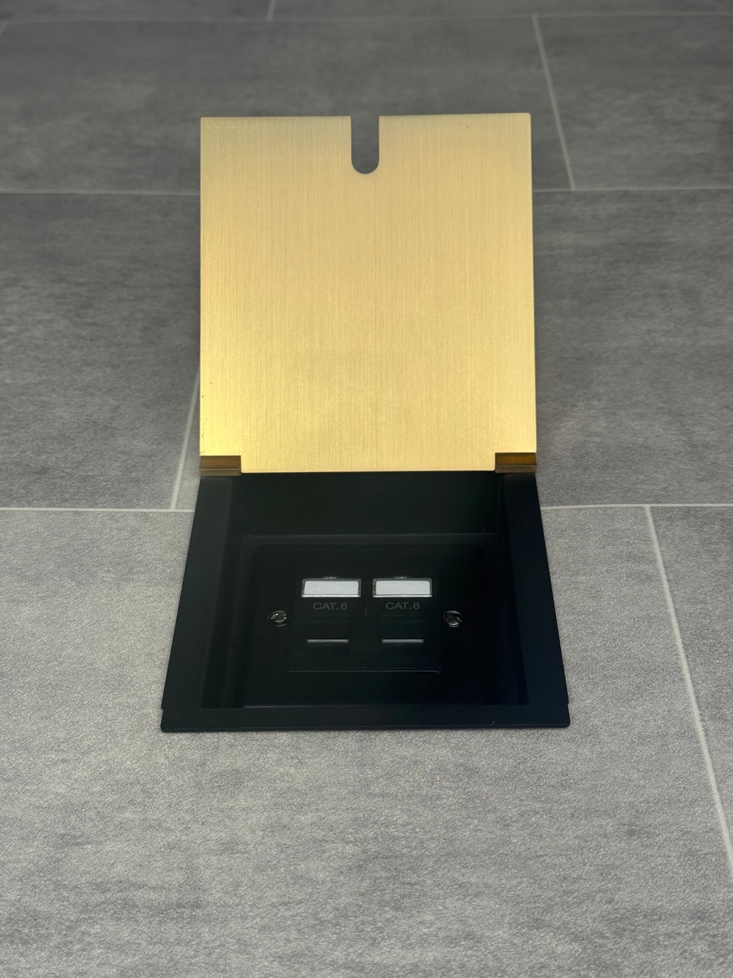 A satin brass finished recessed floor socket with a cover, 2 RJ45 ports, designed for network cable management.