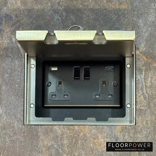 Antique Brass Double Recessed Flush Floor Socket with USB A + C Plug Socket n a stone floor.