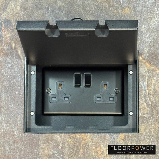 Matt Black Double Recessed Flush Floor Socket with 13A Switched Plug Socket n a stone floor.