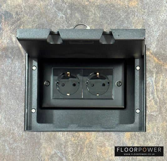 Matt Black Double Recessed Flush Floor Socket with Schuko Plug Socket n a stone floor.