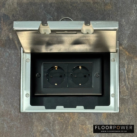 Satin Stainless Double Recessed Flush Floor Socket with Schuko Plug Socket n a stone floor.