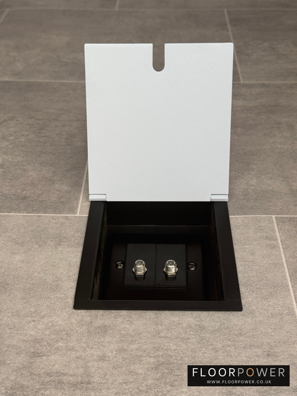 A white recessed floor socket with a 2 gang (double) satellite socket, set in a tiled floor.