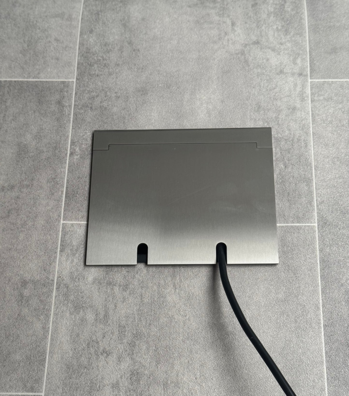 Double Satin Stainless Recessed Floor Socket With Lid Closed Flat Showing Just Cable Coming Out If The Socket - Front On View.