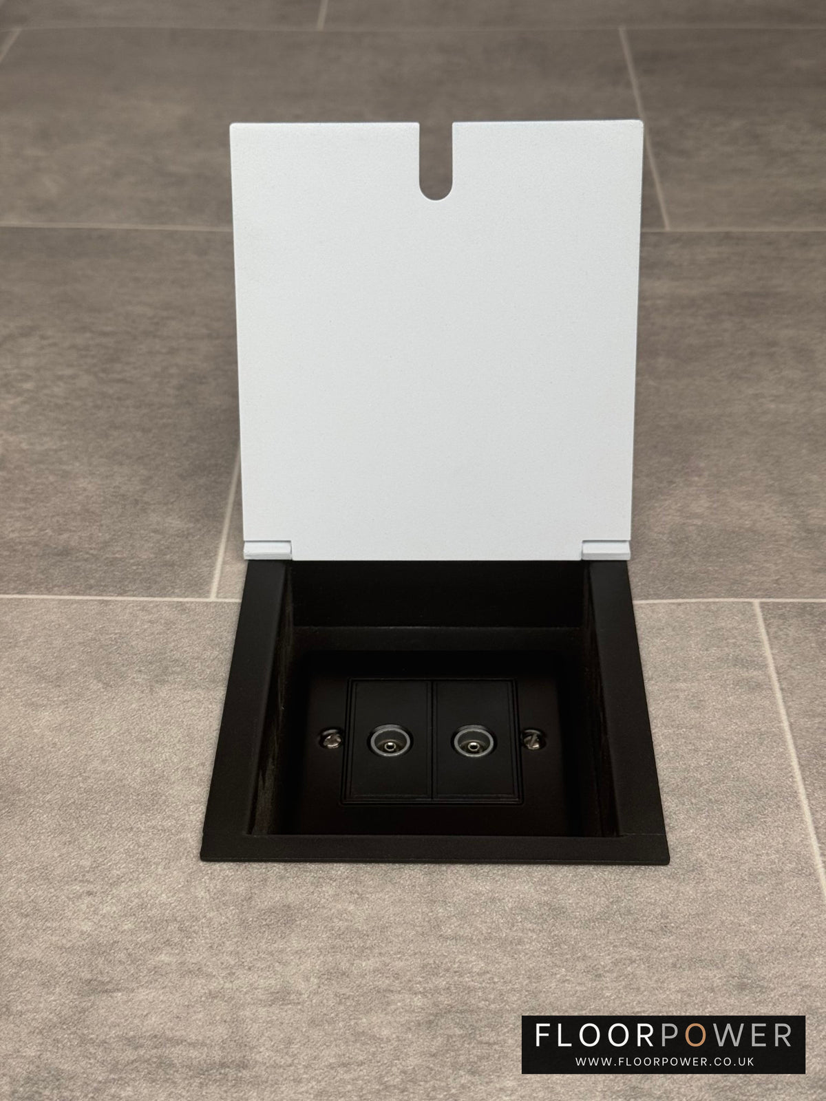 A white recessed floor socket with a opened lid revealing a 2 gang (double) TV socket inside.