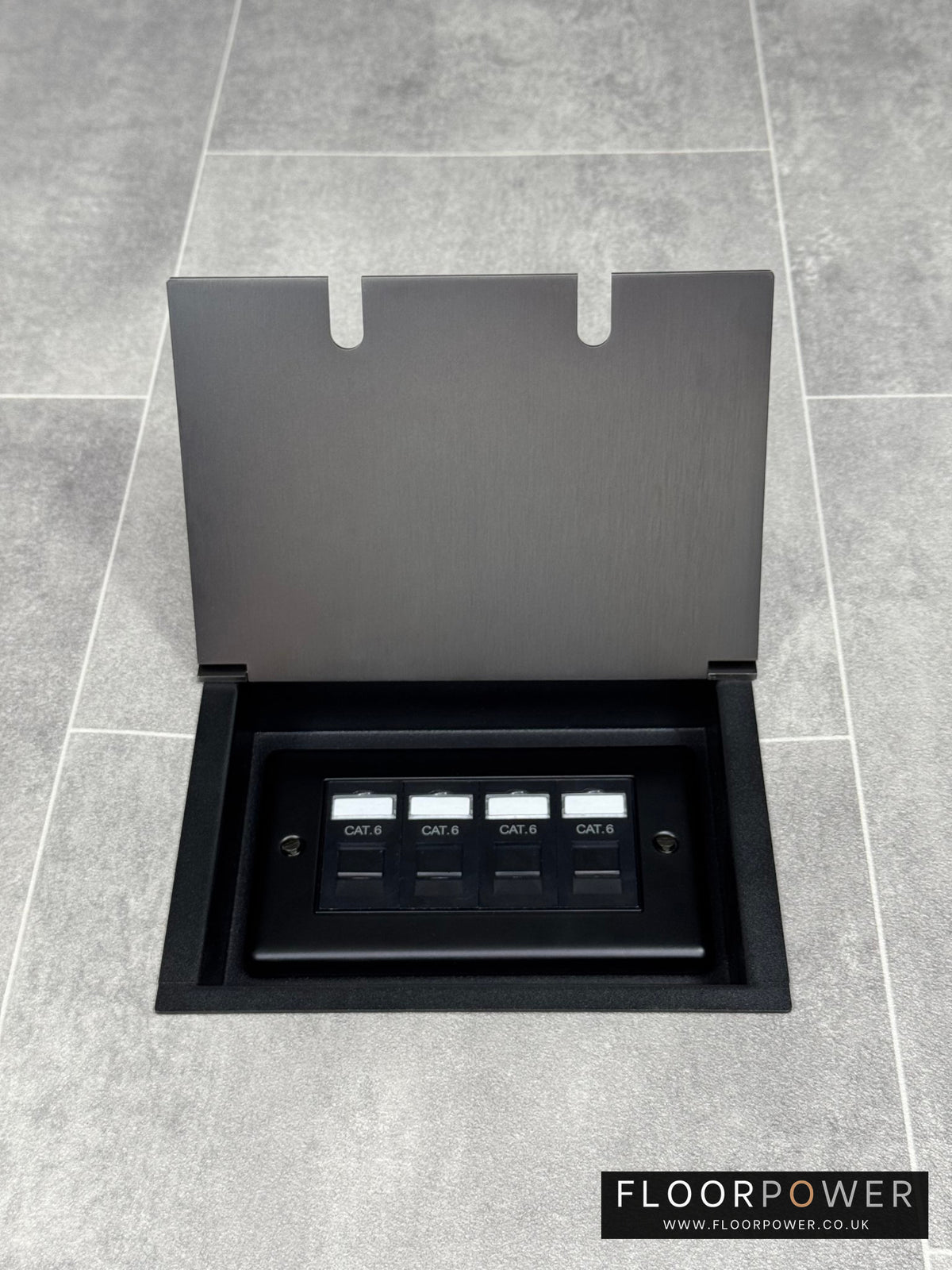 Old bronze double recessed floor socket with a black base installed on a grey floor, opened to show the 4 gang RJ45 cat6 socket.