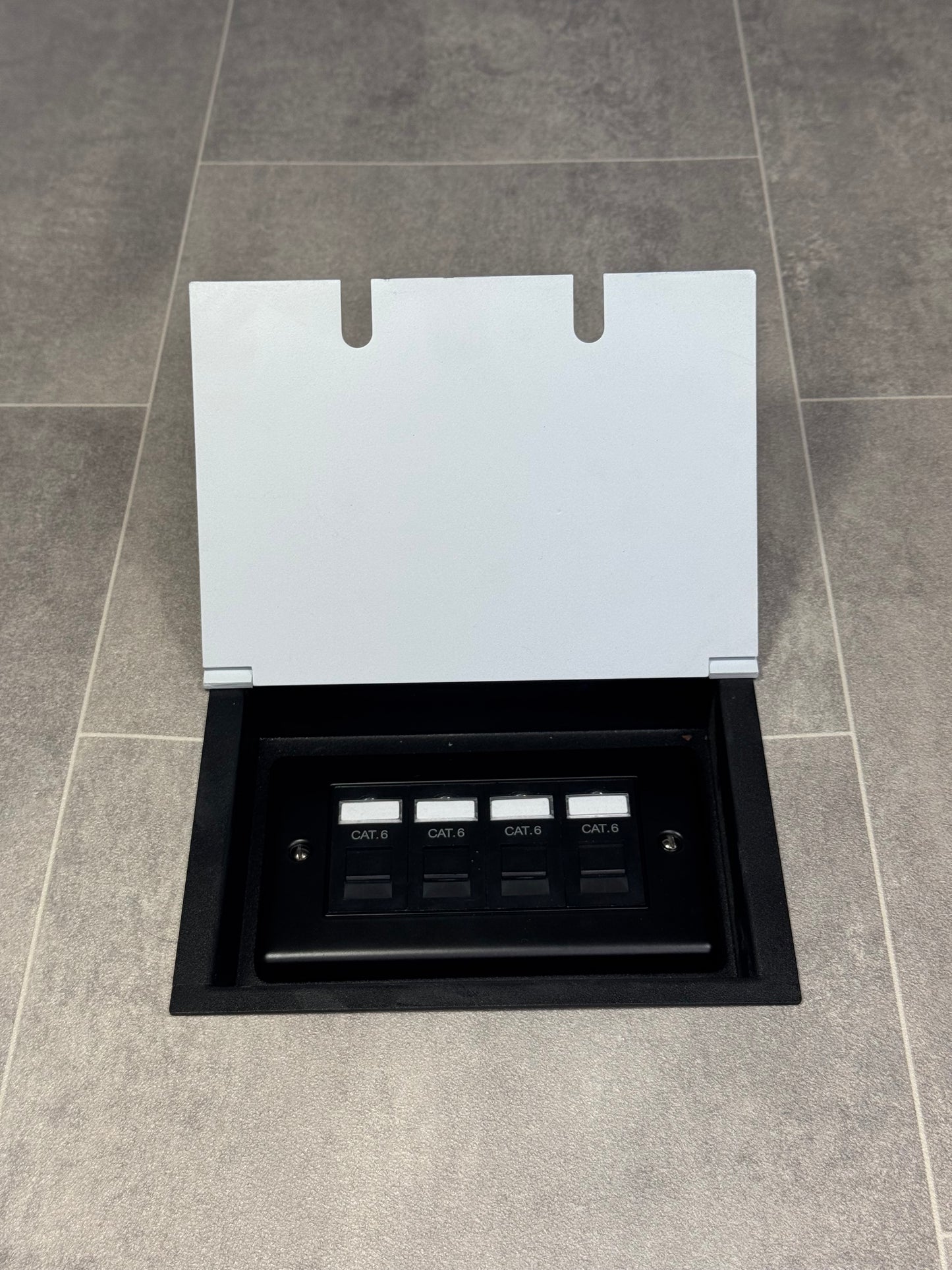 A white double recessed floor socket with a 4 gang RJ45 cat6 socket in a tiled floor.