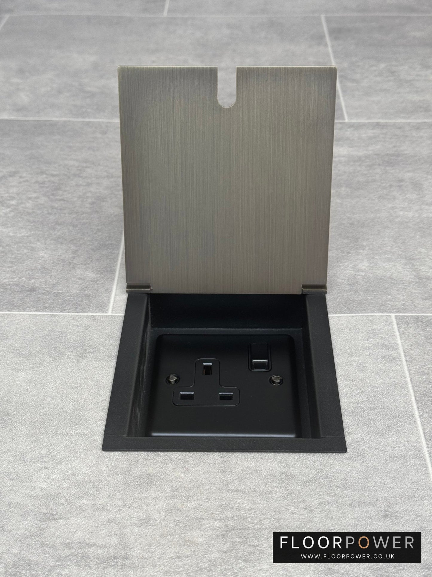 A recessed floor socket with a cover, in antique brass finish, opened to show the 13 Amp socket.