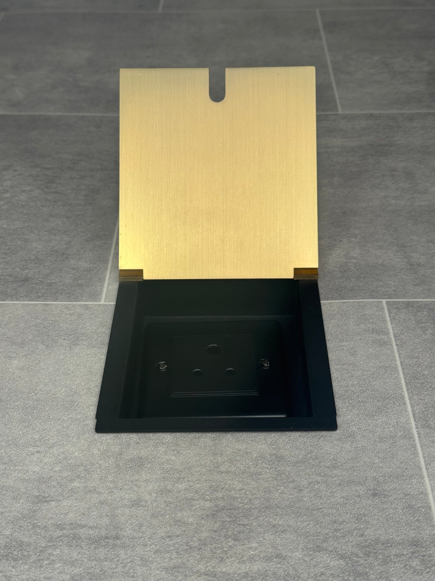 A satin brass recessed floor socket with a single 5 amp round pin socket for lighting, installed in a tiled floor.
