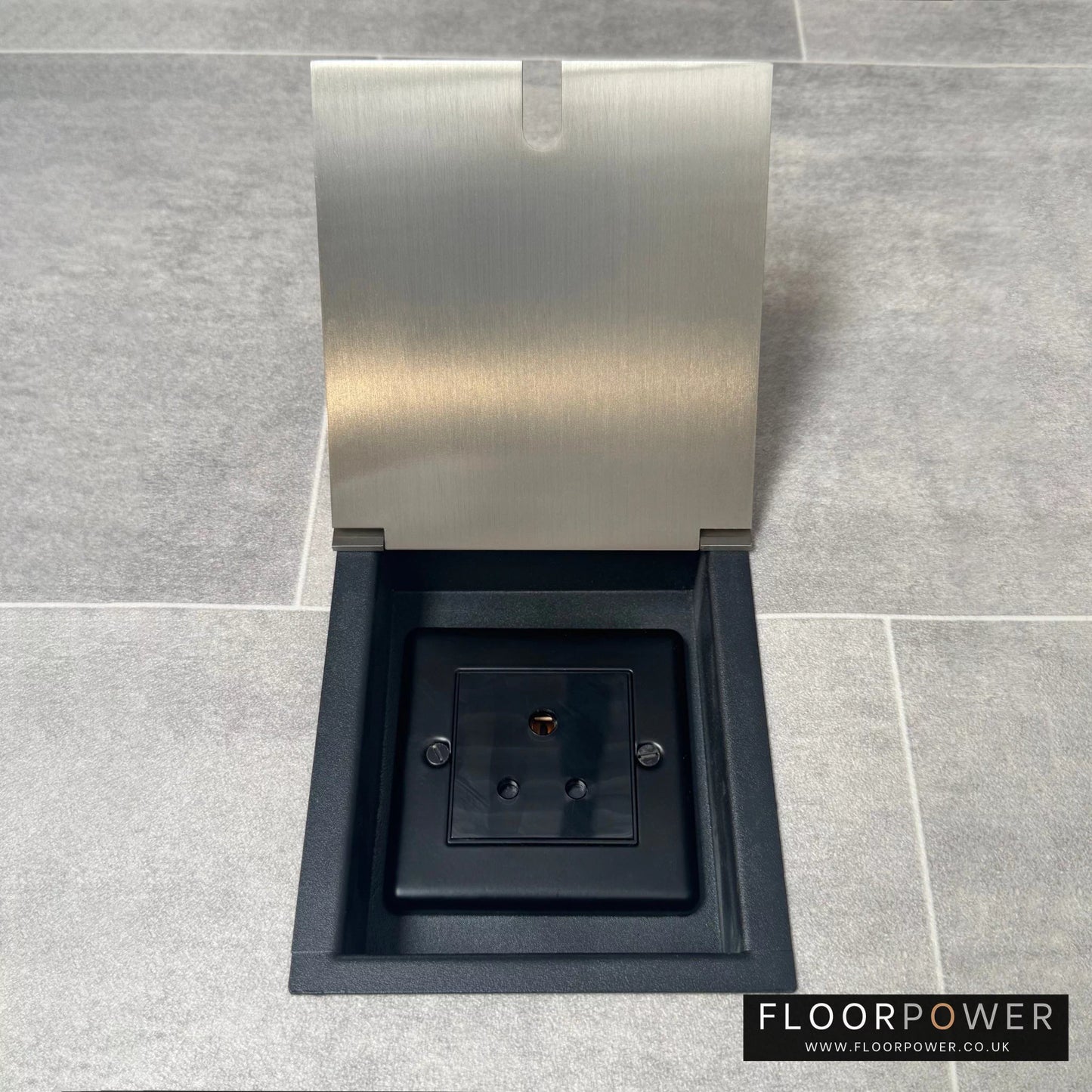 A 5 amp round pin recessed floor socket for lighting with satin nickel finish cover, set against a grey tiled floor.