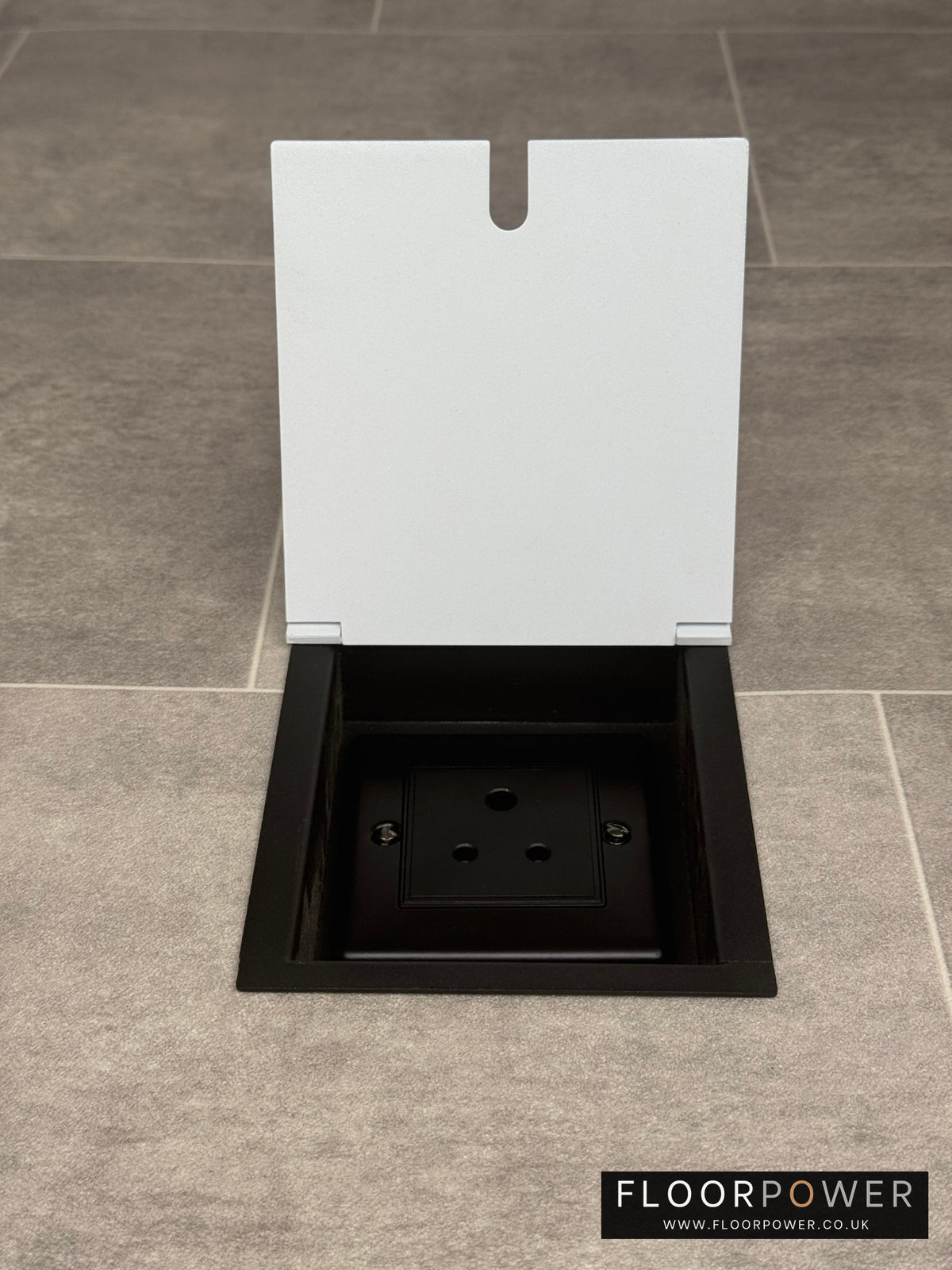 A white recessed floor socket with a single 5 amp round pin socket for lighting, installed in a tiled floor.