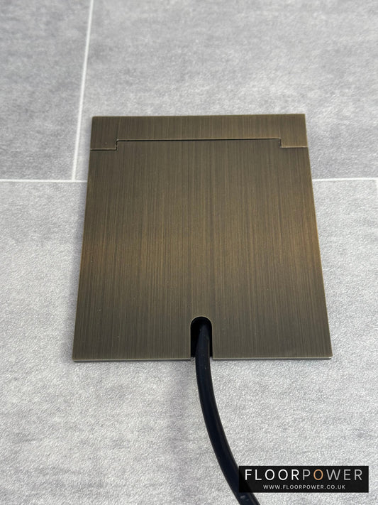 Single Antique Brass Recessed Floor Socket With Lid Closed Flat Showing Just Cable Coming Out If The Socket - Front On View.