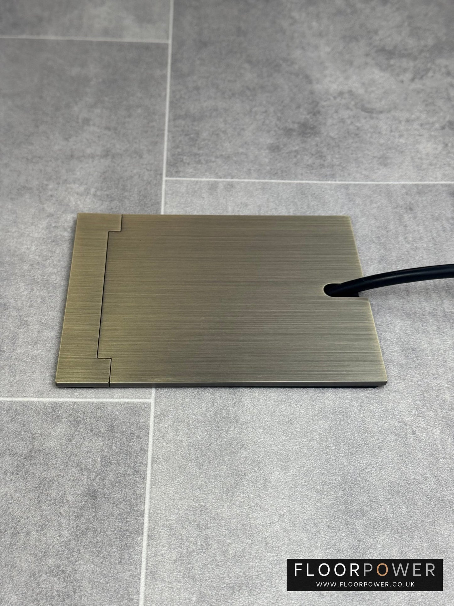 Single Antique Brass Recessed Floor Socket With Lid Closed Flat Showing Just Cable Coming Out If The Socket - Side On View.