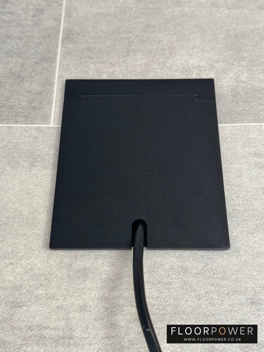 Single Matt Black Recessed Floor Socket With Lid Closed Flat Showing Just Cable Coming Out If The Socket - Front On View.