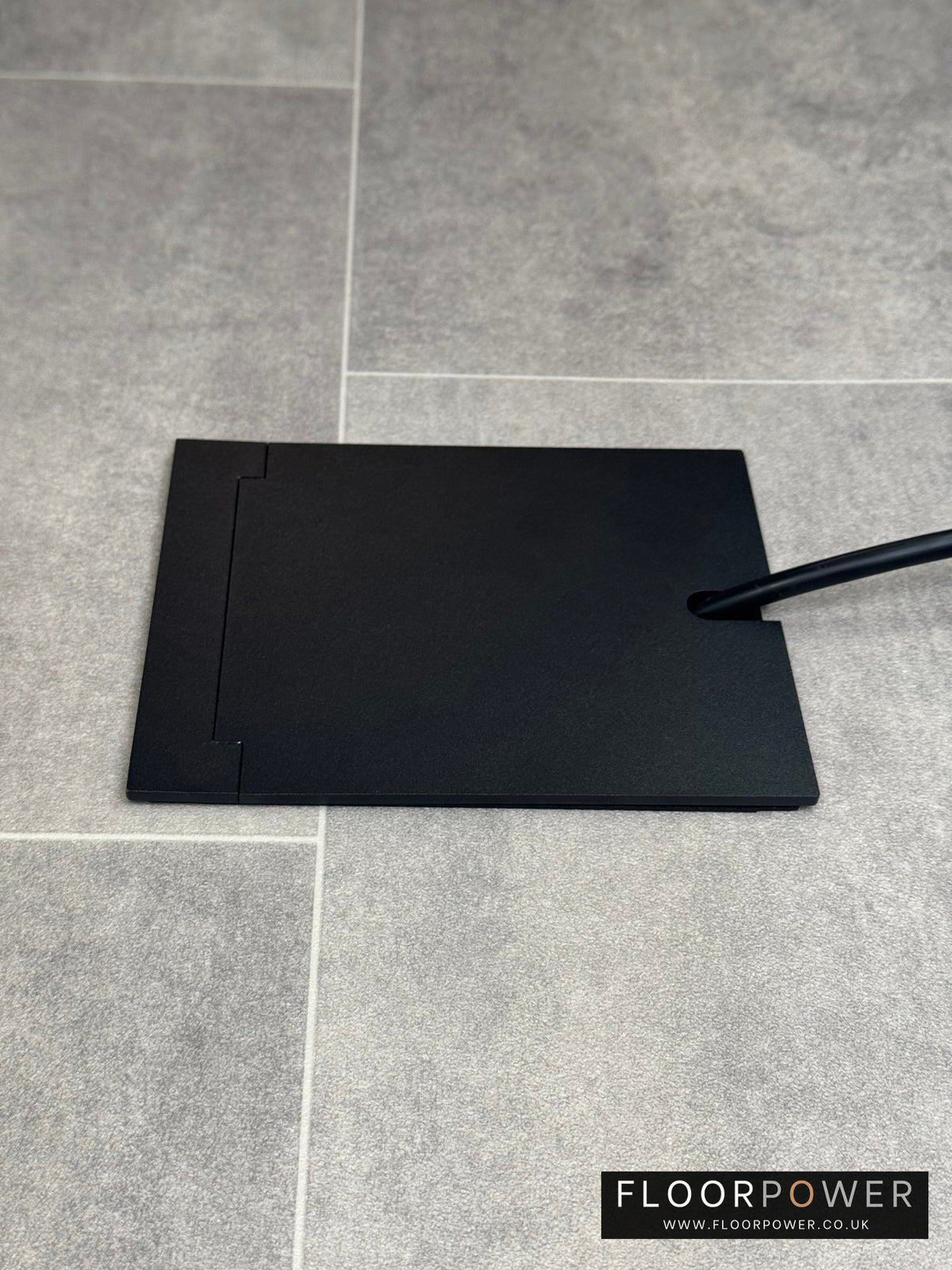 Single Matt Black Recessed Floor Socket With Lid Closed Flat Showing Just Cable Coming Out If The Socket - Side On View.