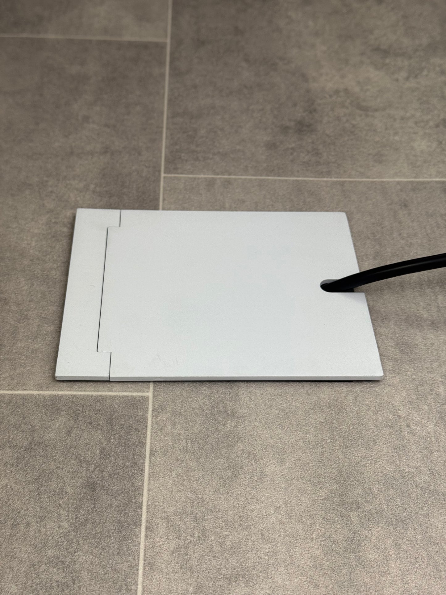 Single Matt White Recessed Floor Socket With Lid Closed Flat Showing Just Cable Coming Out If The Socket - Side On View.