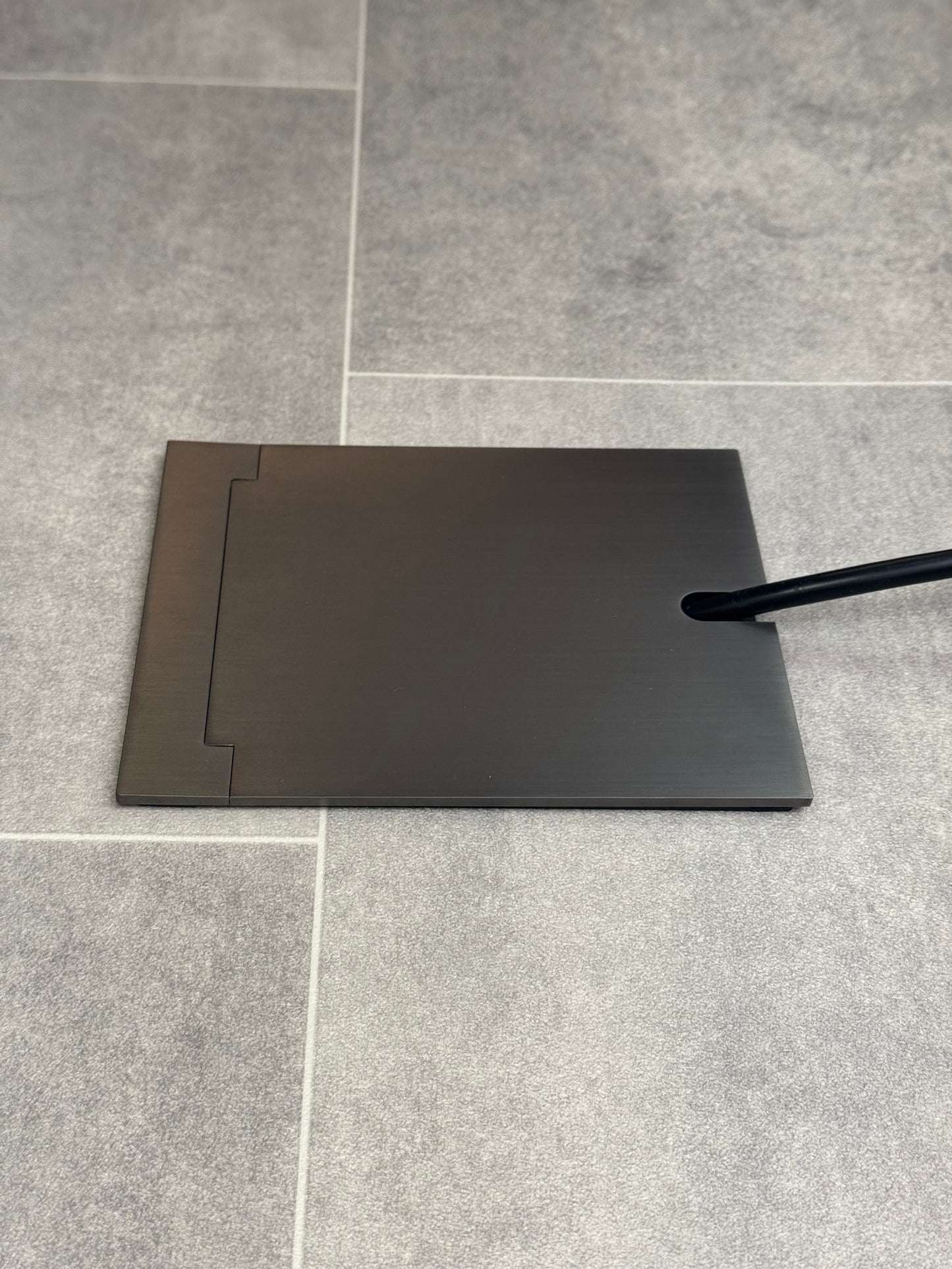 Single Old Bronze Recessed Floor Socket With Lid Closed Flat Showing Just Cable Coming Out If The Socket - Side On View.