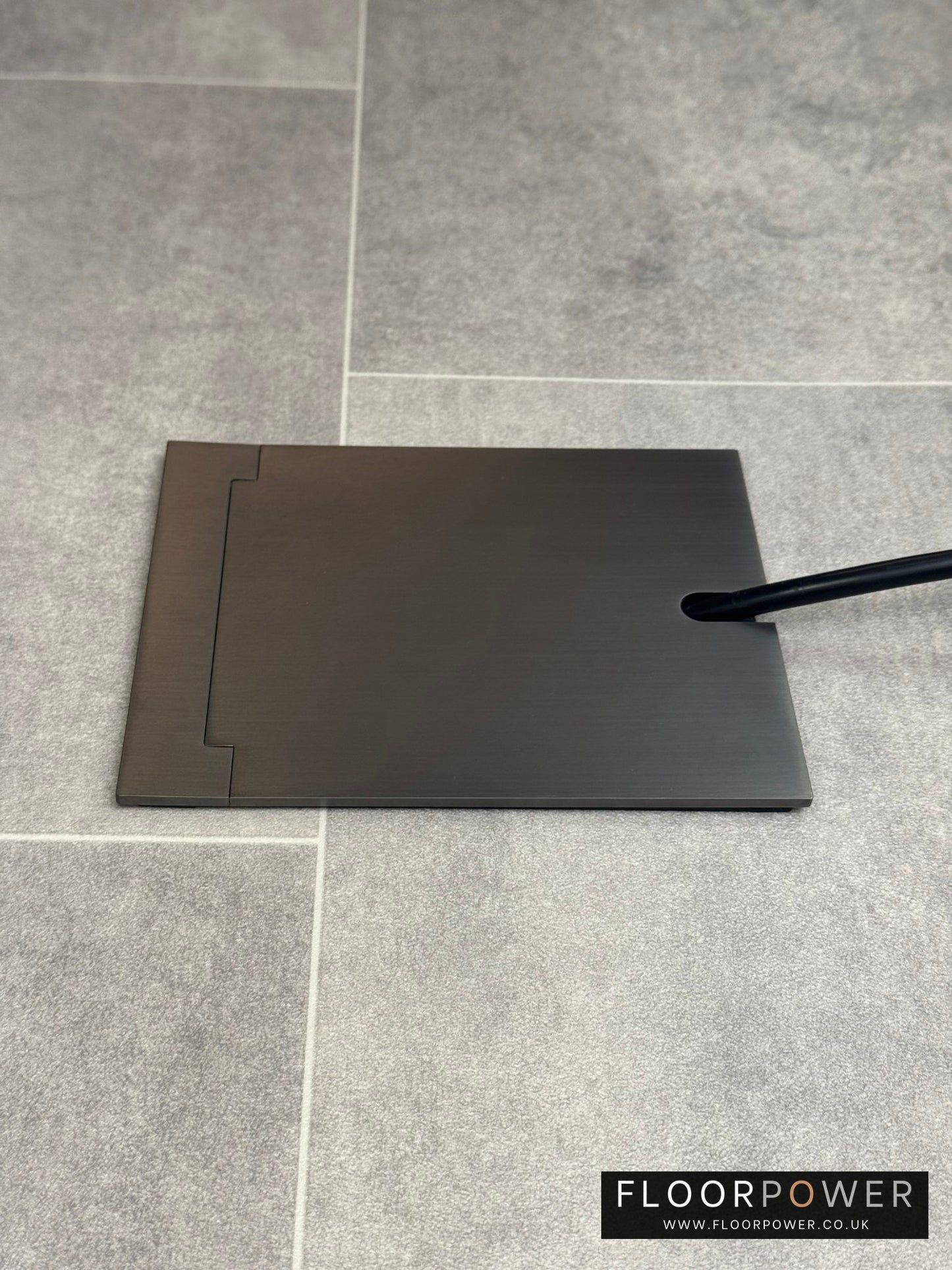 Single Old Bronze Recessed Floor Socket With Lid Closed Flat Showing Just Cable Coming Out If The Socket - Side On View.