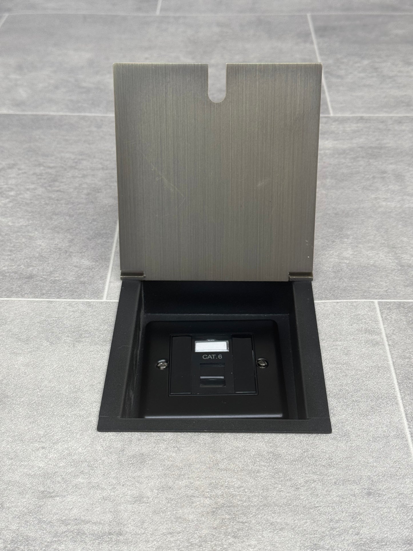 A antique brass finish recessed floor socket with a black base, opened to reveal the internal Cat6 RJ45 socket.