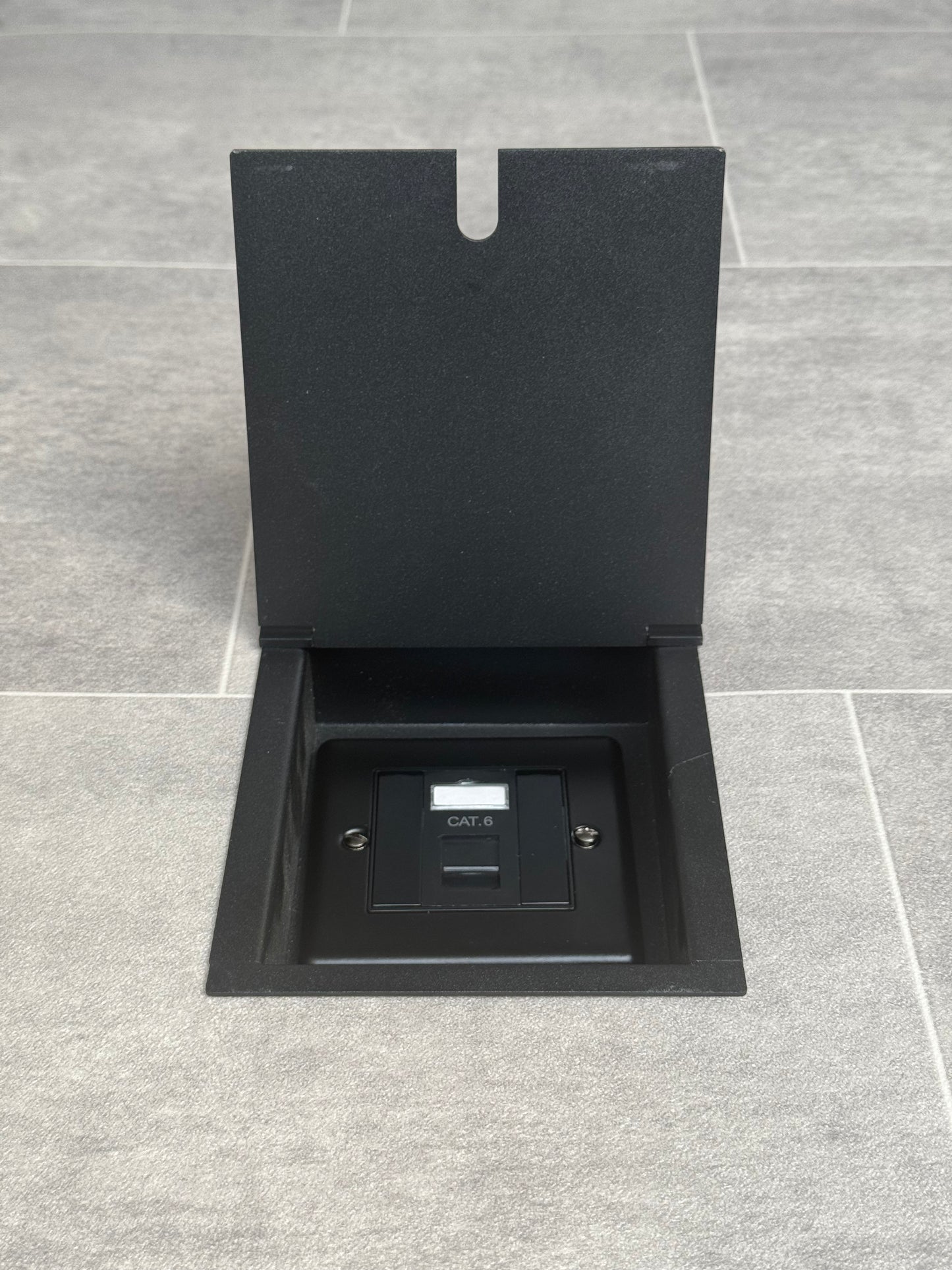 A matt black recessed floor socket with a black base, opened to reveal the Cat6 RJ45 socket.