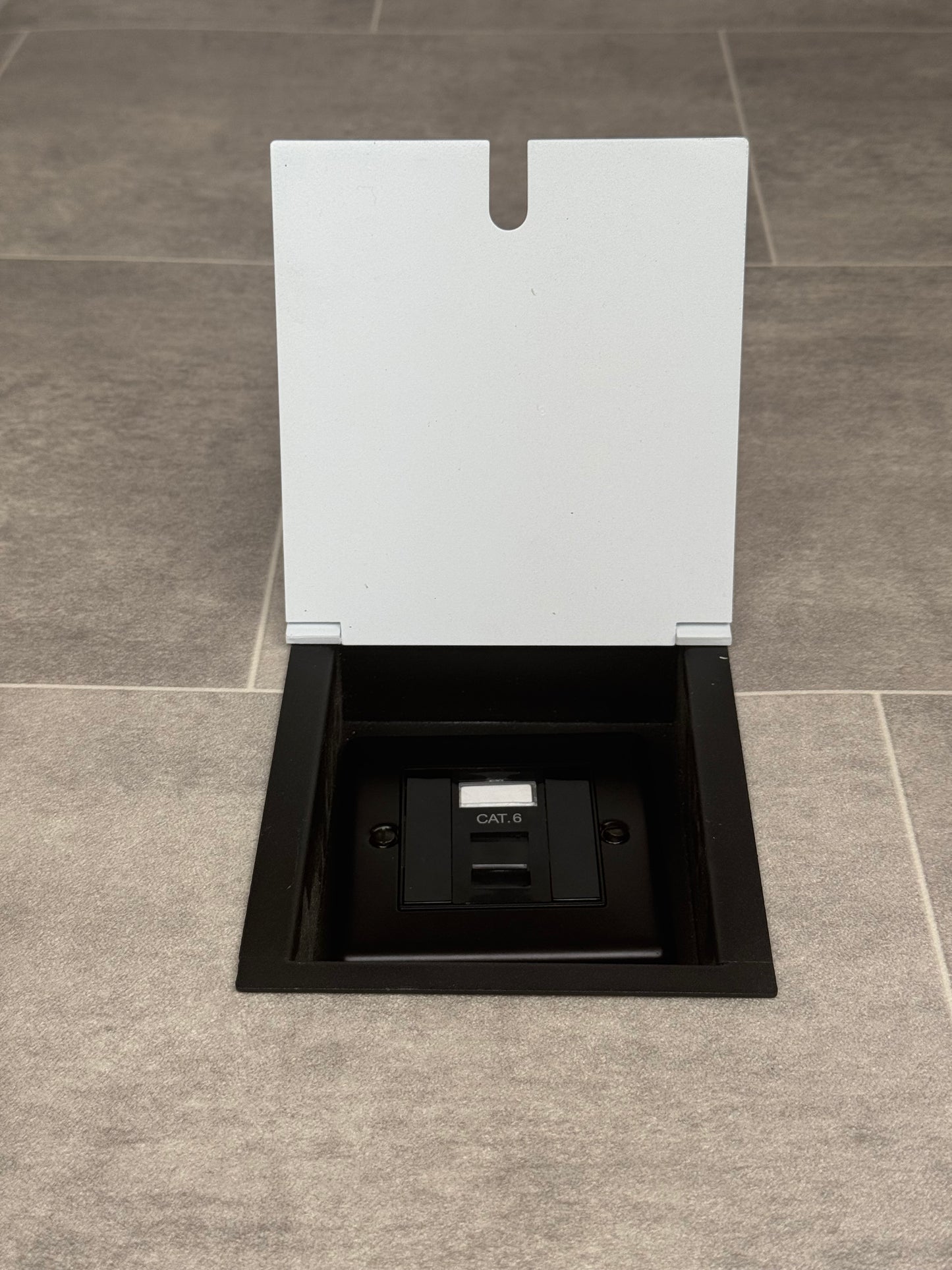 A white recessed floor socket with a black base, opened to reveal the Cat6 RJ45 socket.