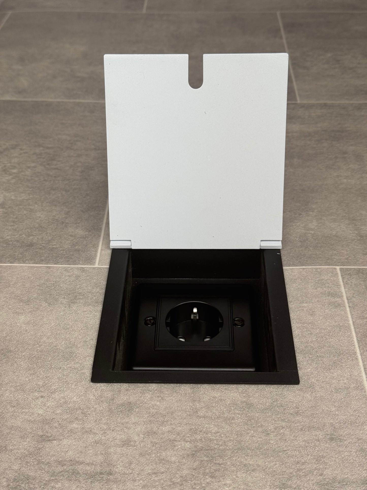 White recessed floor socket with a single Schuko (European) plug socket.