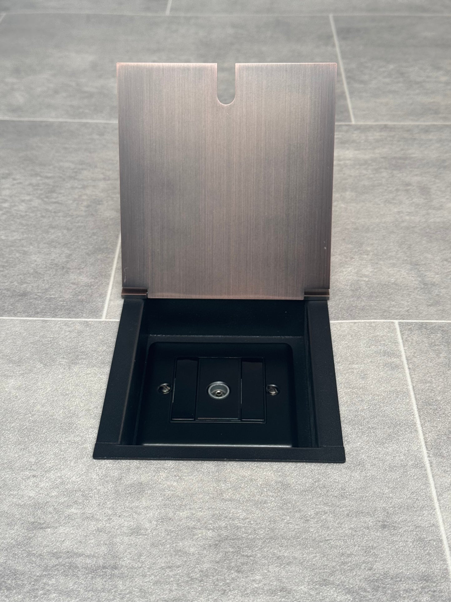 Antique copper recessed floor socket with a single gang TV socket, opened to show the socket.