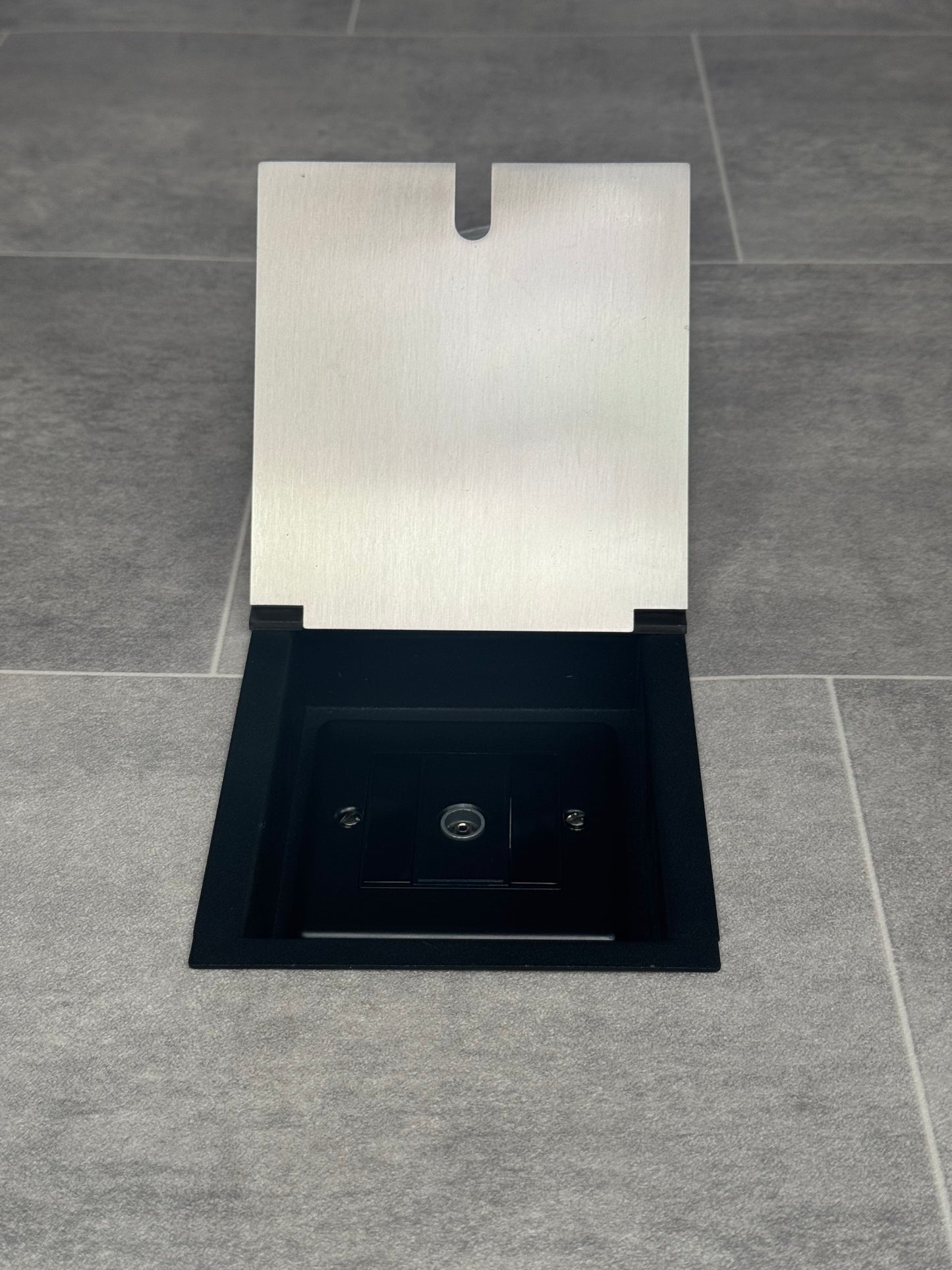 A satin stainless recessed floor socket with a single 1 gang TV aerial socket, shown open, installed in a floor.