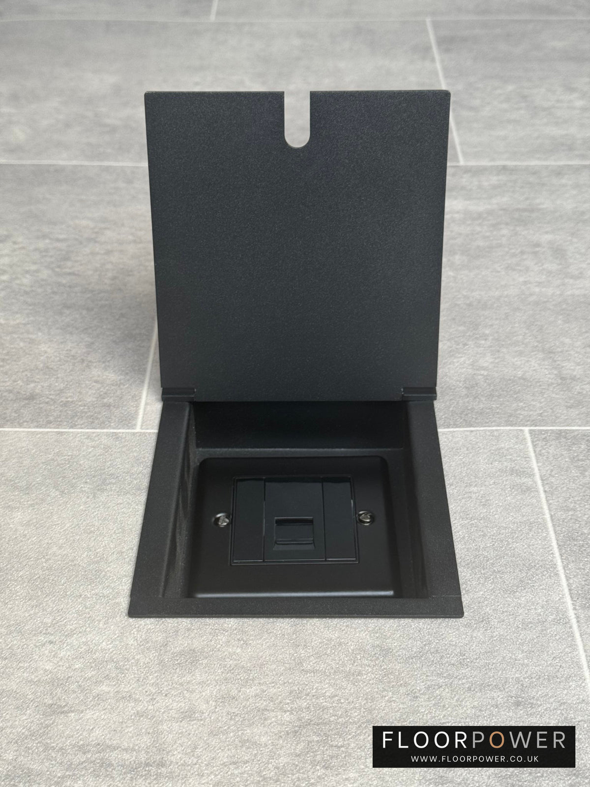 Matt black recessed floor socket with a single phone socket, shown in an open position with its cover lifted to reveal the socket.