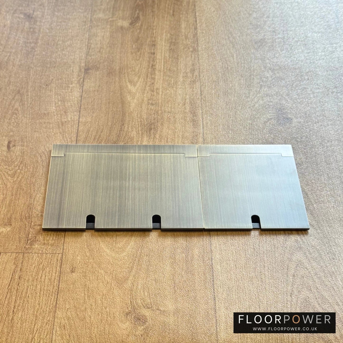 Closed Triple Recessed Floor Socket in Antique Brass on wood floor.
