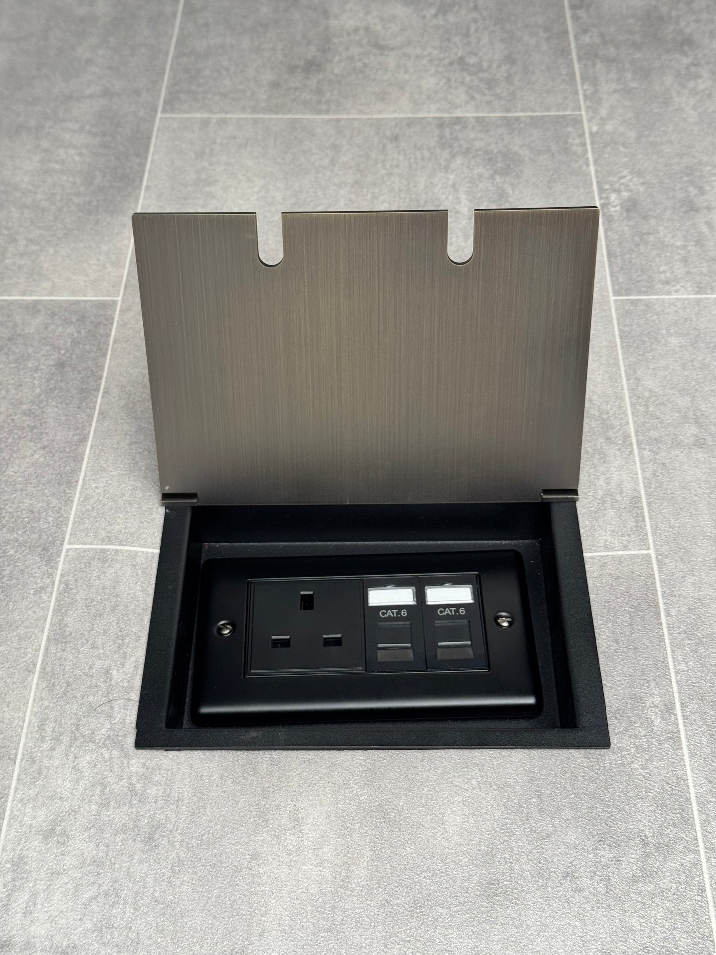 Recessed floor socket in antique brass with a double box containing one 13amp unswitched socket and two RJ45 sockets, set in a tiled floor setting.