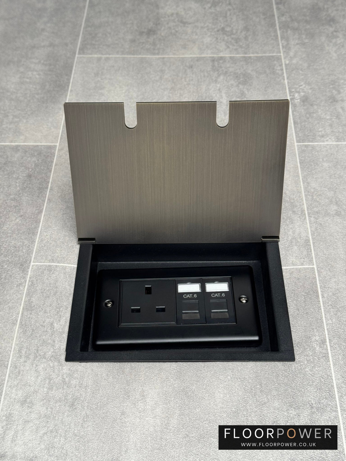 Recessed floor socket in antique brass with a double box containing one 13amp unswitched socket and two RJ45 sockets, set in a tiled floor setting.