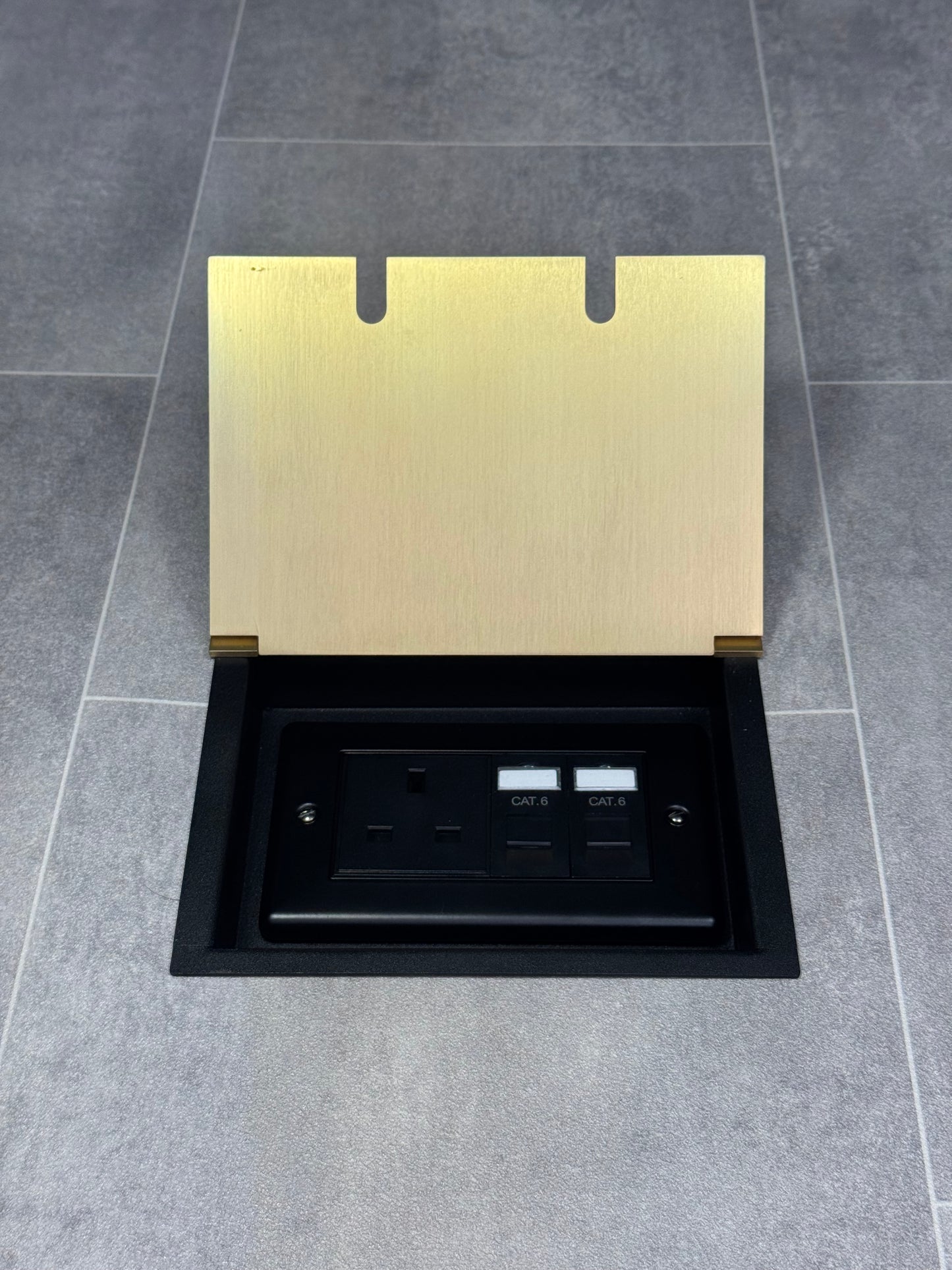Double recessed floor socket in satin brass containing one 13amp unswitched socket and two RJ45 sockets in a tiled floor.