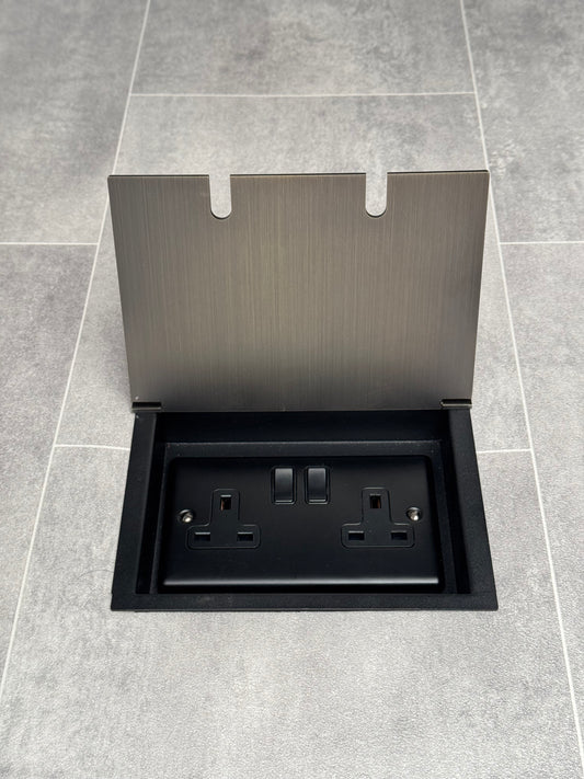 Antique brass recessed floor socket with a double 13amp switched plug socket, in a tiled floor.