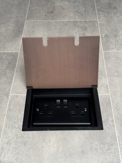 A double 13 Amp switched plug socket in an antique copper recessed floor socket.