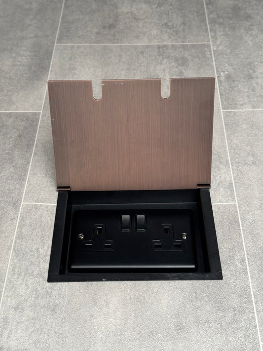 A double 13 Amp switched plug socket in an antique copper recessed floor socket.