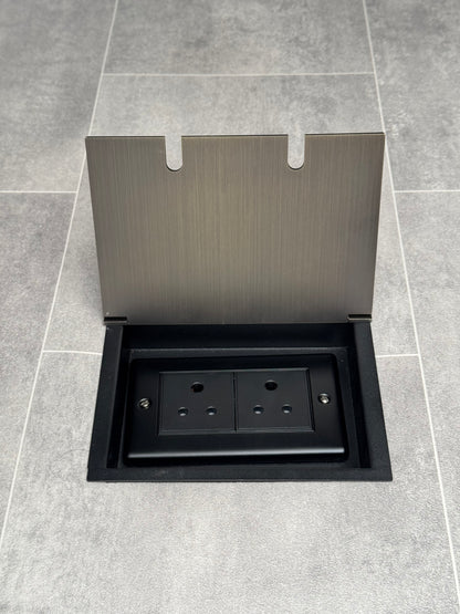 Double 5 amp recessed floor socket for lighting with antique brass lid set into the floor.