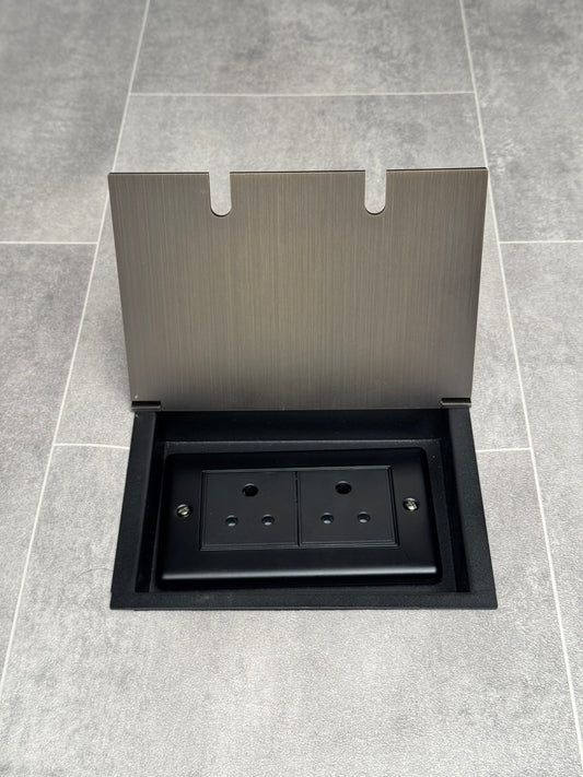 Double 5 amp recessed floor socket for lighting with antique brass lid set into the floor.