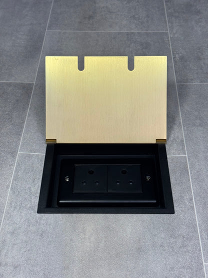 Double 5 amp recessed floor socket for lighting with satin brass lid set into the floor.