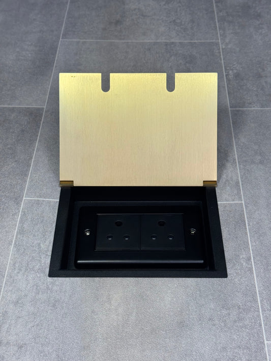 Double 5 amp recessed floor socket for lighting with satin brass lid set into the floor.
